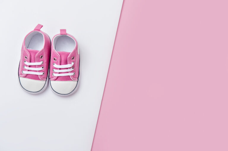Cute pink baby girl sneakers close up on pink and white background